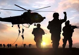 Military helicopter with soldiers preparing for landing at sunset.