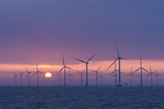Offshore wind turbines at sunset, renewable energy source, ocean, clean power.