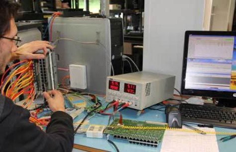 Technician testing electronic circuits with advanced equipment in lab.