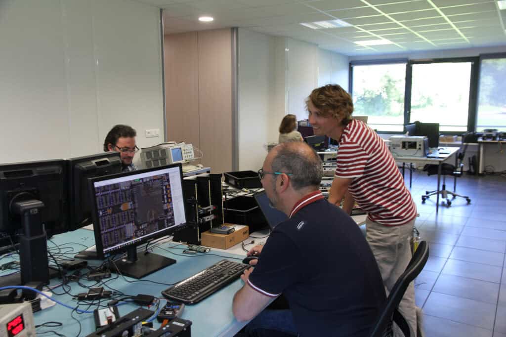 Team collaborating in a high-tech laboratory with computers and electronic equipment.